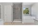 Well-lit bathroom with a shower and separate soaking tub by the window at 3925 Cordano Ln, Lawrenceville, GA 30044