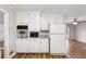 White kitchen with built-in appliances, granite counters, and wood floors at 1237 Samuel St, Marietta, GA 30008