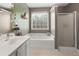 Modern bathroom featuring a soaking tub, separate shower, and large window for natural light in neutral tones at 7810 Rose Ct, Cumming, GA 30040
