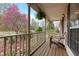 Charming covered front porch with wood flooring, neutral railing, seat, and decorative hanging plant at 7810 Rose Ct, Cumming, GA 30040
