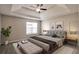 Comfortable main bedroom with tray ceiling, neutral walls, carpet, and bench at end of bed at 4410 Millenium View Ct, Snellville, GA 30039
