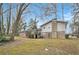Back exterior view of a charming brick home with a deck and yard surrounded by mature trees at 5140 Cowart Ct, Powder Springs, GA 30127