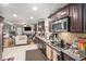 Well-equipped kitchen with stainless steel appliances, dark wood cabinets, and an open view to the living area at 5140 Cowart Ct, Powder Springs, GA 30127