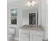 Bathroom vanity with a granite countertop, white cabinets, mirror and natural light from a window at 3856 Lockaby Way, Lawrenceville, GA 30044