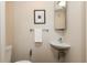 Neutral-toned half bathroom with a small sink, toilet, mirror, and a decorative art print at 1661 La France Ne St # 314, Atlanta, GA 30307