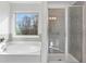 Bathroom showcases tub, large window with exterior view and glass enclosed shower at 3786 Lockaby Way, Lawrenceville, GA 30044