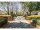 Gated driveway entrance with brick pillars, lush landscaping, and mature trees leads to the estate at 3847 Sweet Bottom Dr, Duluth, GA 30096