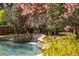 Gorgeous backyard pool featuring a stone waterfall feature and lush, mature landscaping at 3847 Sweet Bottom Dr, Duluth, GA 30096