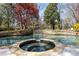 Beautiful inground pool featuring an attached spa and natural stone accents and surrounding mature trees at 3847 Sweet Bottom Dr, Duluth, GA 30096