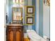 Charming powder room with striped walls, a marble countertop vanity, and ornate gold framed artwork and mirror at 3847 Sweet Bottom Dr, Duluth, GA 30096