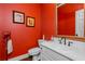 Red powder room featuring a framed mirror, a white vanity, and decorative wall art at 3655 Brisbane Dr, Marietta, GA 30062