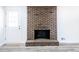 Close-up of a brick fireplace with gray wood-look flooring, white walls, and a white door at 6175 Marilla St, Douglasville, GA 30135