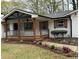 Charming home featuring a covered porch, white brick facade, dark shutters and a beautifully landscaped front yard at 3533 Johns Rd, Tucker, GA 30084