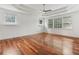 A large bedroom with wood floors, white walls, large windows, and a tray ceiling with a ceiling fan at 4540 Hastings Dr, Cumming, GA 30041