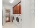 Laundry room with front load washer and dryer, dark wood cabinets, and tile floors at 4540 Hastings Dr, Cumming, GA 30041