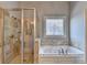 Well-appointed bathroom with a glass-enclosed shower, soaking tub, and decorative window accents at 3006 Cambridge Hill Dr, Dacula, GA 30019