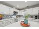 Bright kitchen features white cabinets, an island with stone countertops, modern appliances, and decorative tile backsplash at 7750 Silversmith Dr, Cumming, GA 30028