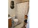 A bathroom with a floral shower curtain and a dark wooden mask on the wall at 315 Saratoga Pl, Riverdale, GA 30296