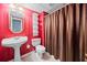 Cozy bathroom showcasing red striped walls, a classic pedestal sink, toilet, and a shower with a curtain at 1421 Briarcliff Dr, Woodstock, GA 30189
