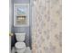 Bright bathroom featuring a toilet with a flower patterened shower curtain and window with blinds at 1421 Briarcliff Dr, Woodstock, GA 30189