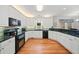 Bright kitchen features white cabinets, hardwood floors, and dark countertops with stainless appliances at 1421 Briarcliff Dr, Woodstock, GA 30189