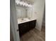 Double sink bathroom with modern light fixture, dark cabinets and wood-look floors at 380 Waterbluff Dr, Mableton, GA 30126