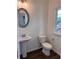 Modern powder room featuring a pedestal sink, oval mirror, and dark hardwood floors at 380 Waterbluff Dr, Mableton, GA 30126