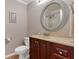 Bathroom with a wooden vanity, oval mirror and a toilet, featuring neutral-colored walls at 3951 Lorien Nw Way, Kennesaw, GA 30152