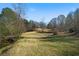 Expansive backyard featuring gentle slopes, mature trees, and a tranquil creek bordering the property at 680 Milligan Creek Rd, Roopville, GA 30170