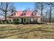 Charming home features a red roof, dormer windows, and a welcoming front porch surrounded by mature landscaping at 680 Milligan Creek Rd, Roopville, GA 30170