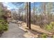 View of wooded backyard with pool, grass, trees, leaves, and sunlight at 8069 Kenstone Ct, Sandy Springs, GA 30350