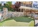 Backyard featuring a putting green, stone wall, lush landscaping and house in background at 8069 Kenstone Ct, Sandy Springs, GA 30350
