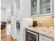 A built-in bar area with a wine refrigerator and glass-front cabinets is conveniently situated near the kitchen at 8069 Kenstone Ct, Sandy Springs, GA 30350
