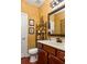 A half bathroom with warm yellow textured walls, wood cabinets, and a decorative mirror at 5877 Stow Dr, Tucker, GA 30084