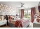 A cozy bedroom features unique wallpaper, plush bedding, and a ceiling fan for added comfort at 5877 Stow Dr, Tucker, GA 30084