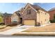 A two-story home featuring a stone and brick facade, manicured landscaping, and an attached garage at 5877 Stow Dr, Tucker, GA 30084