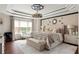 Elegant main bedroom with a tray ceiling, bench, accent wall, and luxurious linens at 5877 Stow Dr, Tucker, GA 30084