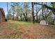 Backyard with bare trees and overgrown grass, also featuring a shed and some corrugated metal at 5273 Crystal Ln, Atlanta, GA 30349