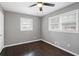 A bright bedroom with dark hardwood floors, a ceiling fan and two windows to let the sun shine in at 5273 Crystal Ln, Atlanta, GA 30349