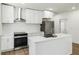 Stylish kitchen with white cabinets, stainless steel appliances and range hood, plus an island with quartz countertop at 936 Byron Sw Dr, Atlanta, GA 30310