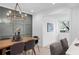 Stylish dining room featuring modern chandelier, wood dining table, accent wall, and seamless access to the kitchen at 112 Rosaire Nw Pl, Atlanta, GA 30327