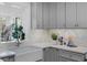 Charming kitchen with a farmhouse sink, gray cabinets, and herringbone backsplash near a bright window at 112 Rosaire Nw Pl, Atlanta, GA 30327
