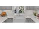 Bright kitchen features a farmhouse sink, gray cabinets, and herringbone backsplash beneath a bright window at 112 Rosaire Nw Pl, Atlanta, GA 30327