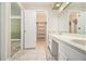Bathroom vanity with double sinks, white cabinets, and a doorway to a walk-in closet at 1472 Hartman Sw Dr, Lilburn, GA 30047