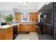 Well-lit kitchen featuring tiled floors, wooden cabinets, and a black refrigerator at 1472 Hartman Sw Dr, Lilburn, GA 30047