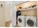 Well-lit laundry room with wood floors, washer, dryer, and ample storage shelving at 1472 Hartman Sw Dr, Lilburn, GA 30047