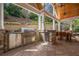 Outdoor kitchen and dining area with stone facade, built-in grill, and wood-paneled ceiling at 4732 Corina Ne Pl, Roswell, GA 30075