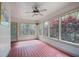 A bright sun room with red wooden floor, white walls, a ceiling fan and many windows at 6227 Braidwood Nw Way, Acworth, GA 30101