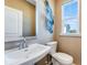 Tan colored powder room with a pedestal sink, modern decorations and a window overlooking the outside at 306 Oldvine Dr, Lawrenceville, GA 30044