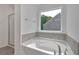 Modern bathtub in main bathroom with tiled backsplash and a window overlooking backyard at 376 Waterbluff Dr, Mableton, GA 30126